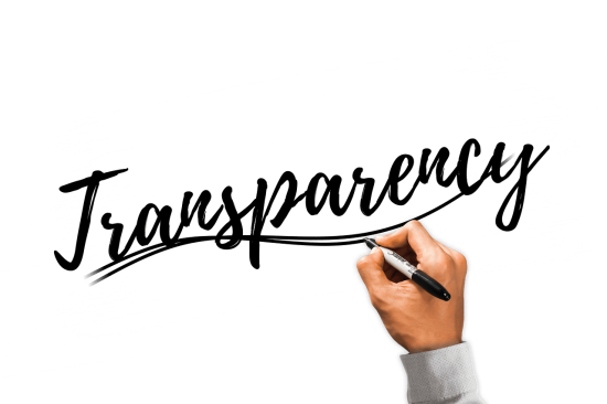 Eine Hand schreibt mit einem schwarzen Stift das Wort Transparenz in englischer Sprache auf einen hellen Untergrund.