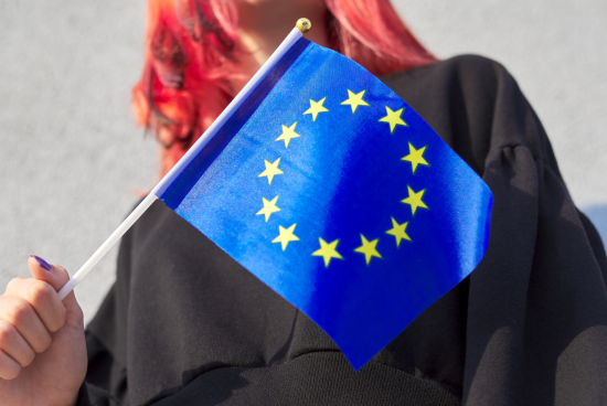 Weiblich gelesene Person hält eine Europafahne in der Hand.